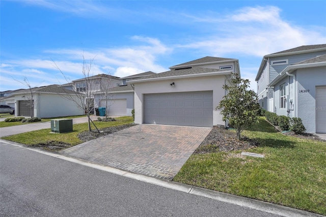 view of front of house with a garage, decorative driveway, a front yard, and stucco siding