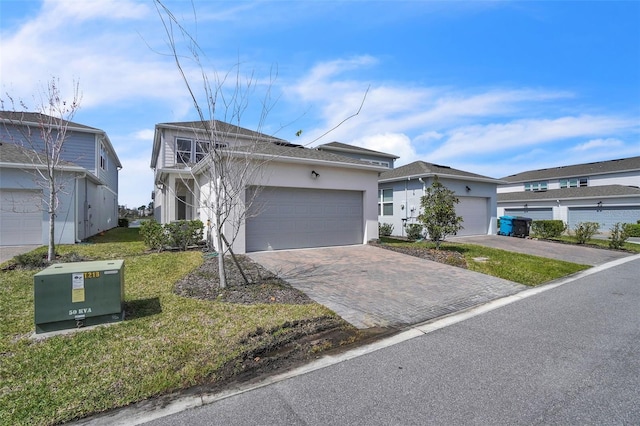 view of front of house with a garage, stucco siding, decorative driveway, and a front lawn