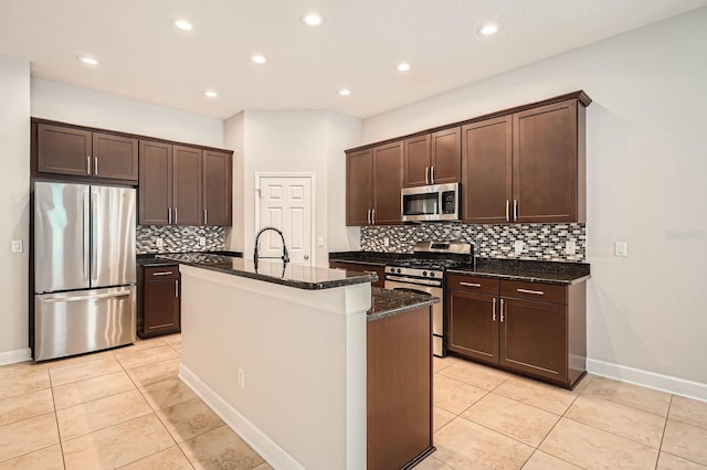 kitchen featuring dark brown cabinetry, light tile patterned floors, stainless steel appliances, and dark stone counters