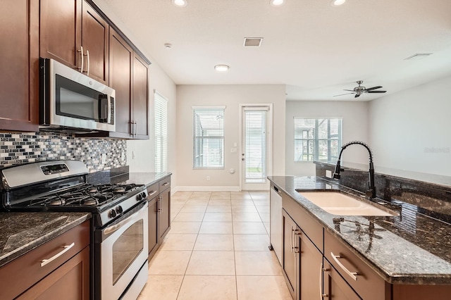 kitchen featuring visible vents, a sink, stainless steel appliances, light tile patterned flooring, and decorative backsplash