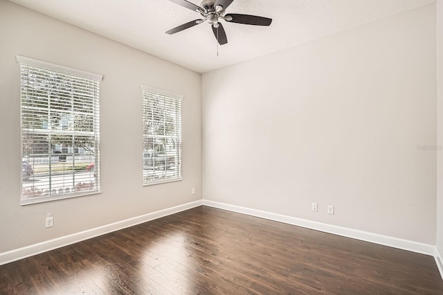 spare room featuring a ceiling fan, dark wood-style flooring, and baseboards