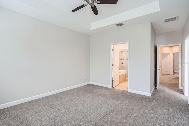 unfurnished bedroom featuring a tray ceiling, visible vents, baseboards, and carpet