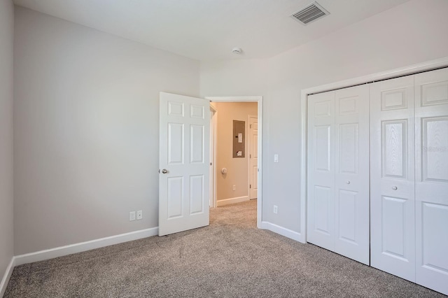 unfurnished bedroom featuring visible vents, electric panel, a closet, carpet flooring, and baseboards