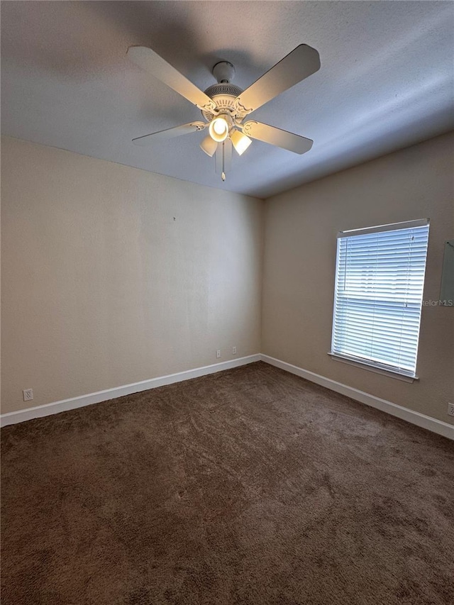 spare room featuring a ceiling fan, baseboards, dark carpet, and a textured ceiling