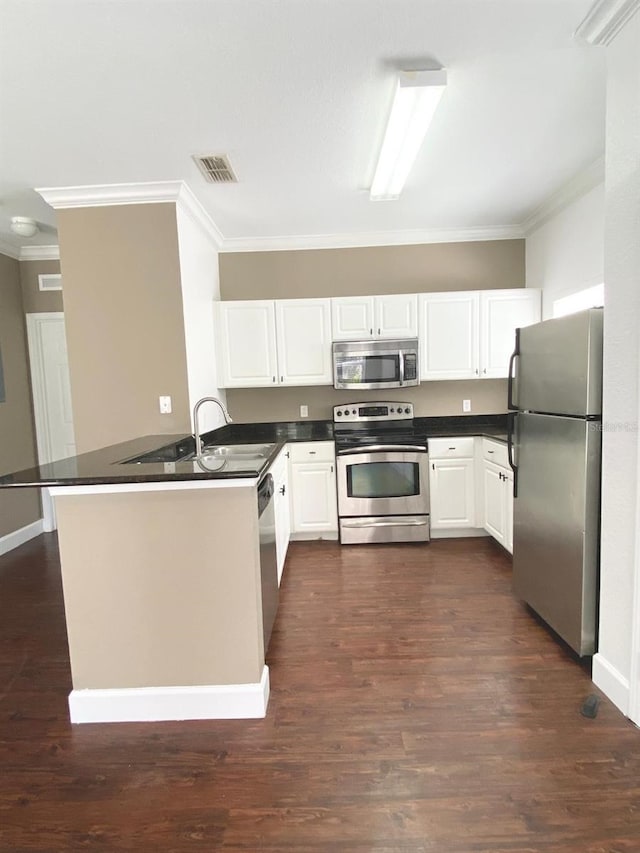 kitchen featuring visible vents, dark countertops, stainless steel appliances, a peninsula, and crown molding