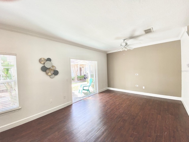 empty room with dark wood finished floors, visible vents, baseboards, and ornamental molding