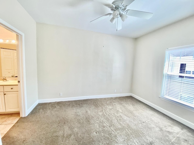 spare room featuring light tile patterned flooring, light colored carpet, baseboards, and ceiling fan