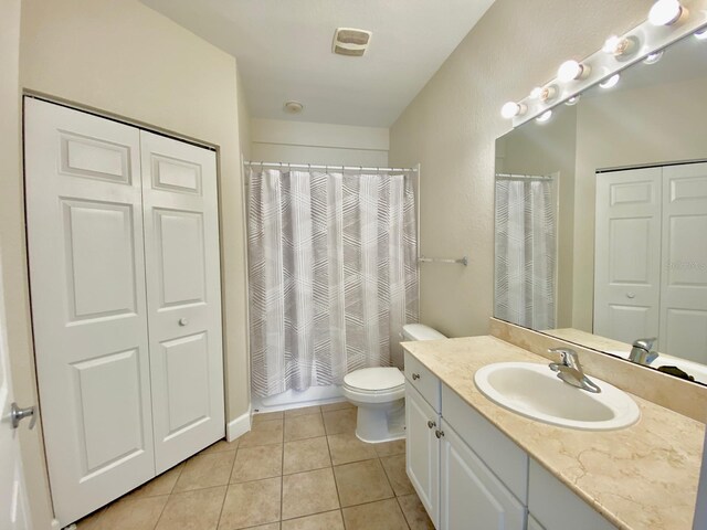 full bathroom with tile patterned flooring, toilet, a shower with shower curtain, a closet, and vanity