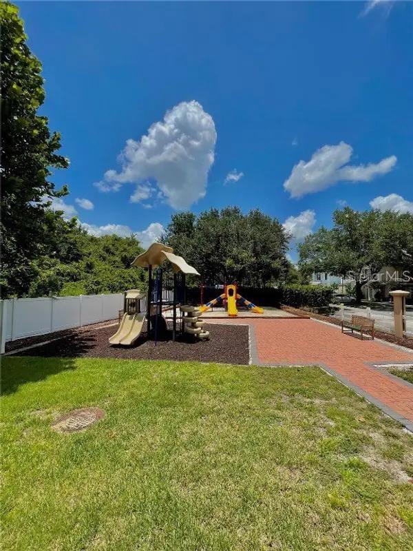 communal playground featuring a lawn and fence