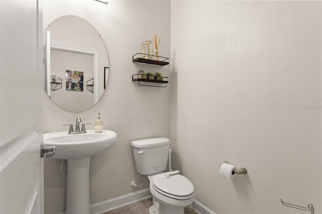 bathroom with a sink, baseboards, toilet, and tile patterned flooring