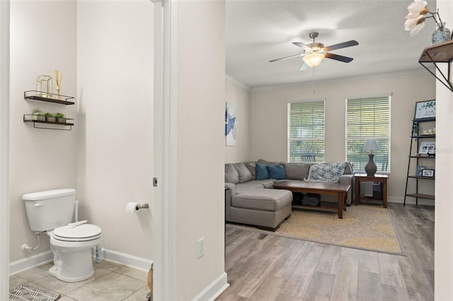 living room featuring a ceiling fan, crown molding, wood finished floors, and baseboards