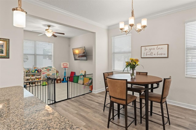 dining space with baseboards, plenty of natural light, wood finished floors, and ornamental molding