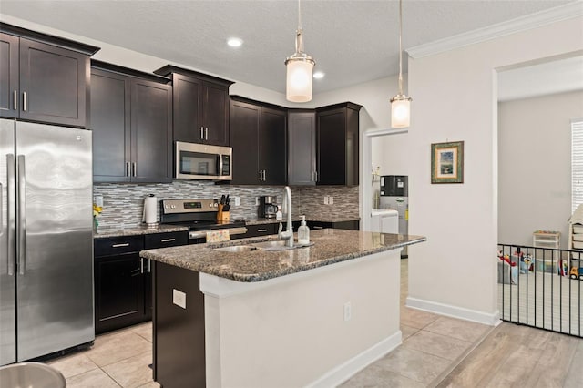 kitchen with backsplash, dark stone countertops, appliances with stainless steel finishes, separate washer and dryer, and a sink