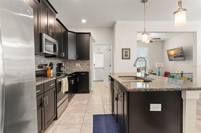 kitchen with tasteful backsplash, light tile patterned floors, appliances with stainless steel finishes, stone countertops, and a sink