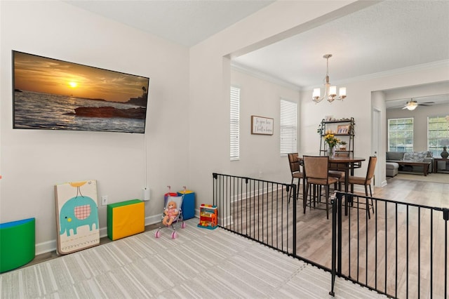 dining space with ceiling fan with notable chandelier, crown molding, baseboards, and wood finished floors