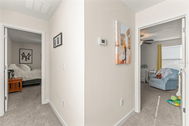 hall with light carpet, visible vents, and baseboards