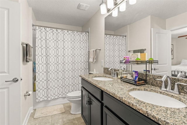 bathroom featuring a textured ceiling, double vanity, toilet, and a sink