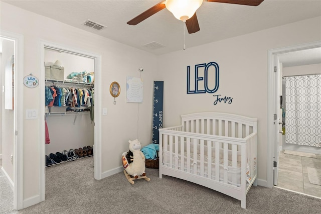 bedroom with carpet, visible vents, a spacious closet, a nursery area, and a closet