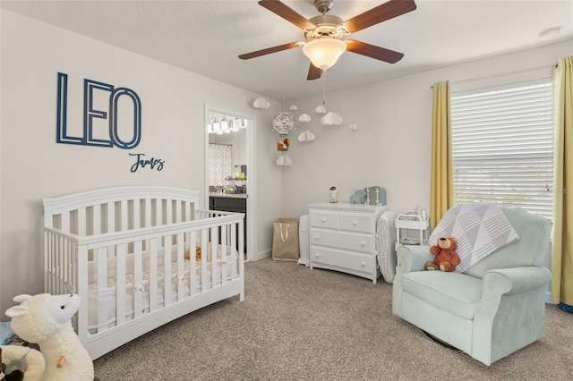 bedroom featuring a crib, a ceiling fan, and carpet floors