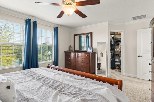 bedroom featuring a spacious closet, visible vents, carpet, and ornamental molding