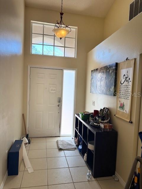 entryway with a high ceiling, light tile patterned floors, baseboards, and visible vents