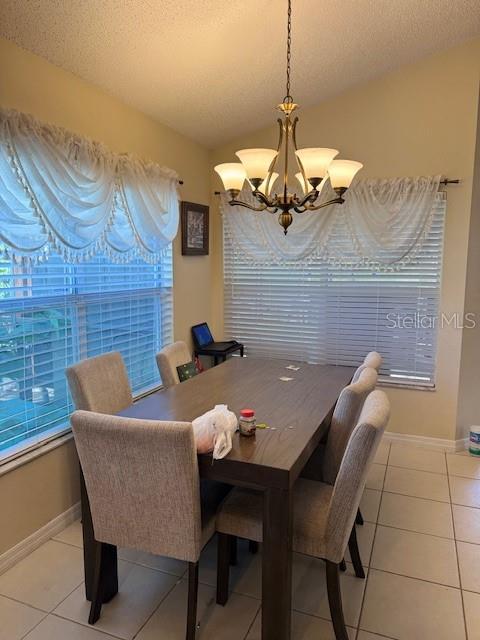 dining room with baseboards, a notable chandelier, light tile patterned flooring, and a textured ceiling