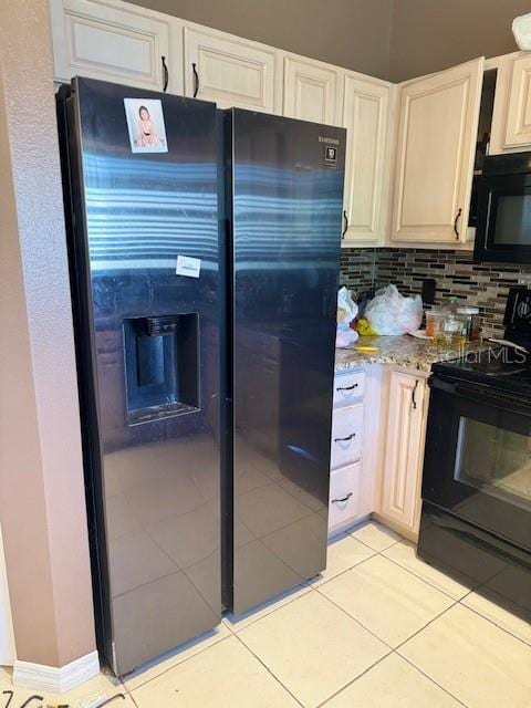 kitchen with light tile patterned floors, light stone countertops, decorative backsplash, black appliances, and white cabinets