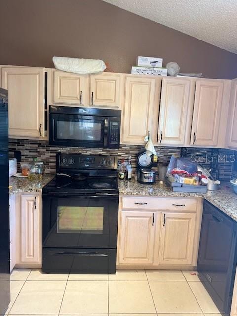 kitchen with lofted ceiling, black appliances, light tile patterned flooring, and light brown cabinetry