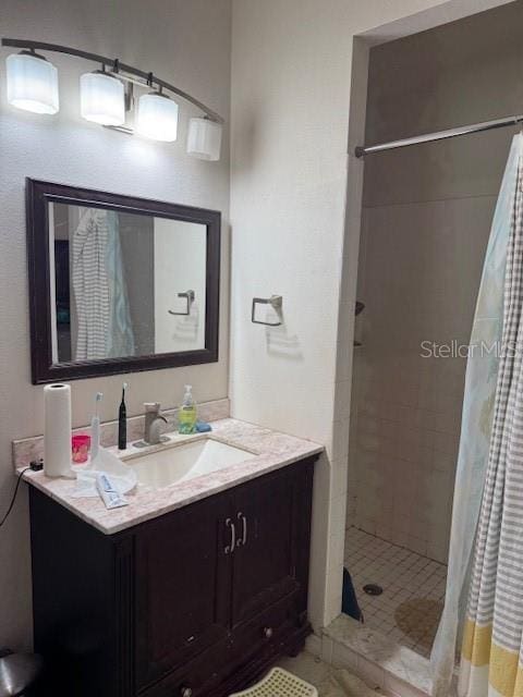 full bath featuring a tile shower and vanity