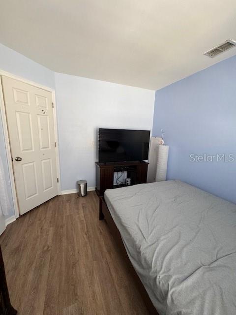 bedroom with wood finished floors, visible vents, and baseboards