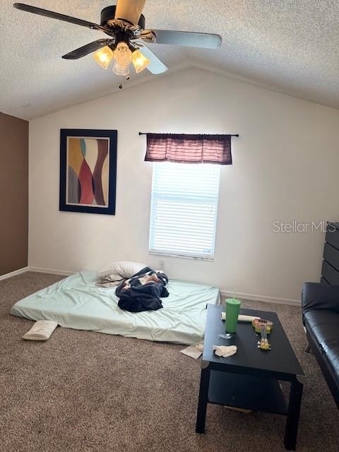 bedroom featuring vaulted ceiling, carpet flooring, and a textured ceiling