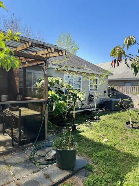 rear view of property with central air condition unit, a yard, and fence