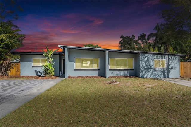 view of front of property with stucco siding, a front lawn, and fence