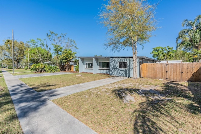 view of front of house featuring stucco siding, driveway, a gate, fence, and a front yard