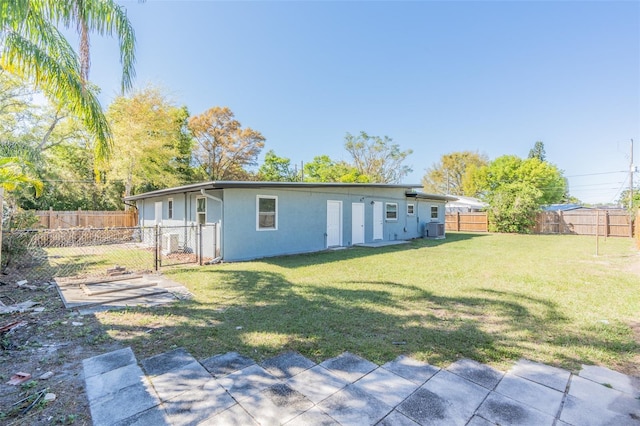 back of house featuring central air condition unit, a yard, a fenced backyard, and stucco siding