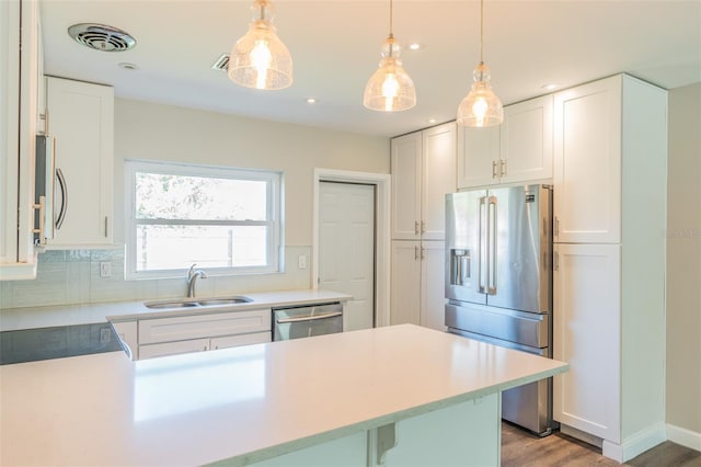 kitchen featuring a sink, stainless steel appliances, visible vents, and decorative light fixtures