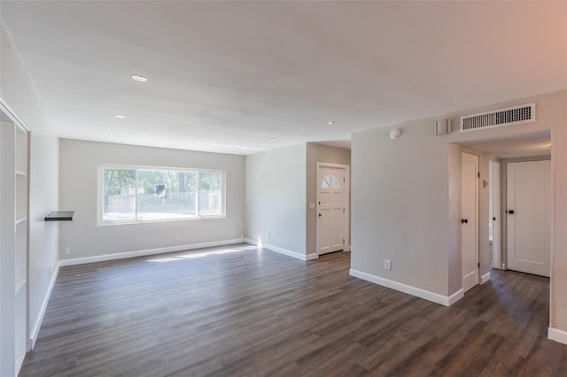 spare room featuring visible vents, baseboards, and dark wood finished floors