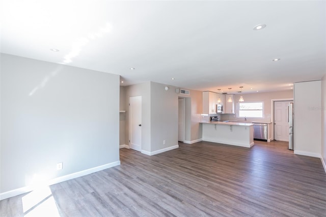 unfurnished living room with recessed lighting, visible vents, baseboards, and wood finished floors