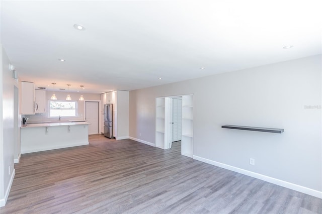 unfurnished living room featuring recessed lighting, light wood-type flooring, and baseboards