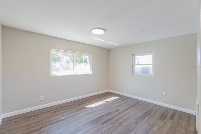 spare room with a wealth of natural light, baseboards, and wood finished floors