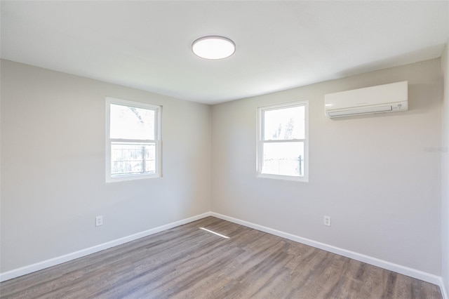 spare room featuring plenty of natural light, a wall mounted air conditioner, and baseboards