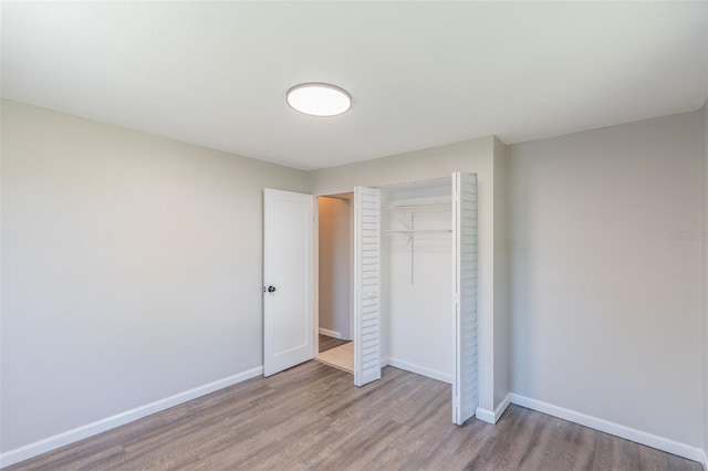 unfurnished bedroom with a closet, baseboards, and wood finished floors