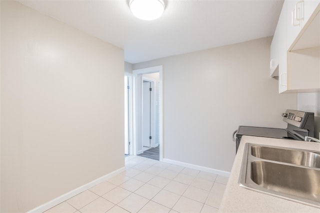 kitchen featuring electric range, baseboards, white cabinets, and a sink