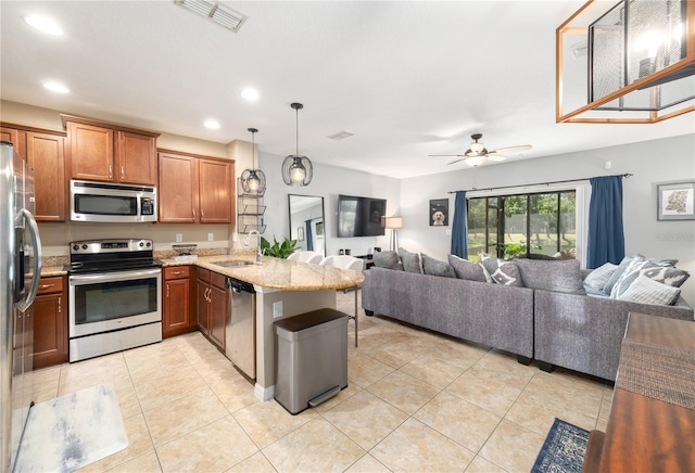 kitchen featuring visible vents, open floor plan, stainless steel appliances, a peninsula, and light stone countertops