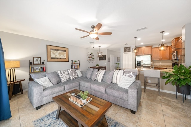 living area featuring light tile patterned floors, visible vents, baseboards, and a ceiling fan