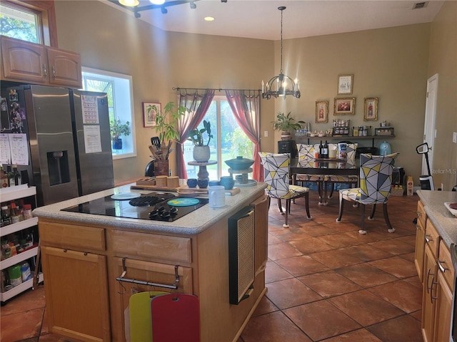 kitchen with stainless steel fridge with ice dispenser, light countertops, hanging light fixtures, a notable chandelier, and black electric cooktop