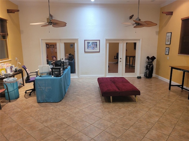 living area featuring french doors, a high ceiling, ornamental molding, and a ceiling fan