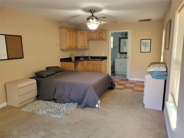 bedroom featuring visible vents, light colored carpet, baseboards, and a sink