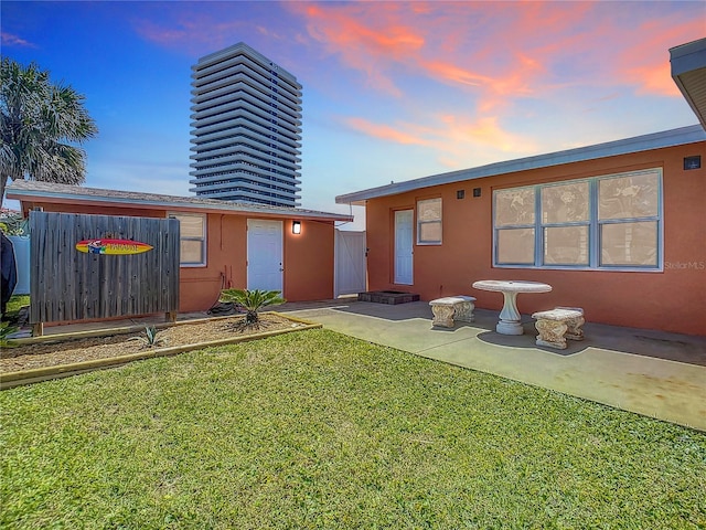 back of property featuring a yard, a patio area, and stucco siding