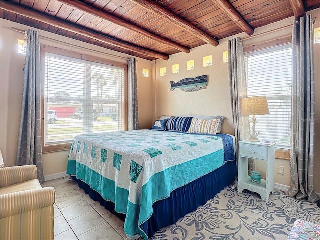 bedroom with light tile patterned floors, beamed ceiling, multiple windows, and wooden ceiling